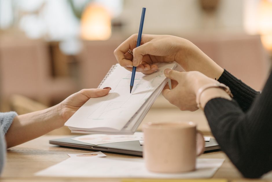 Close-up of hands collaborating on sketches during a business meeting.