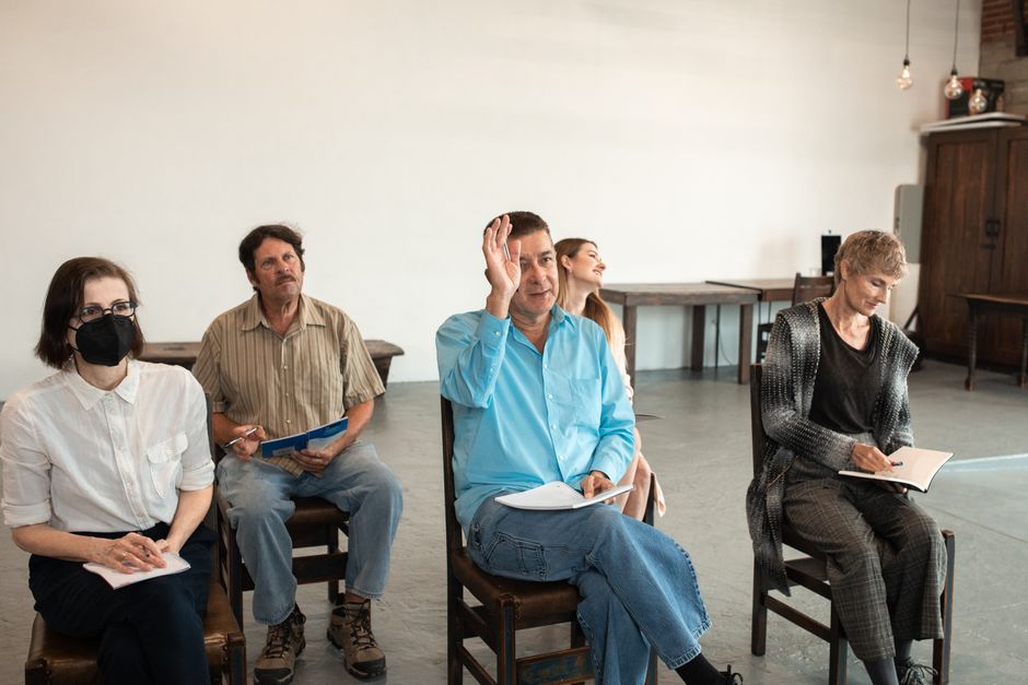 Group of adults sitting on chairs indoors, taking notes and participating actively in discussion.