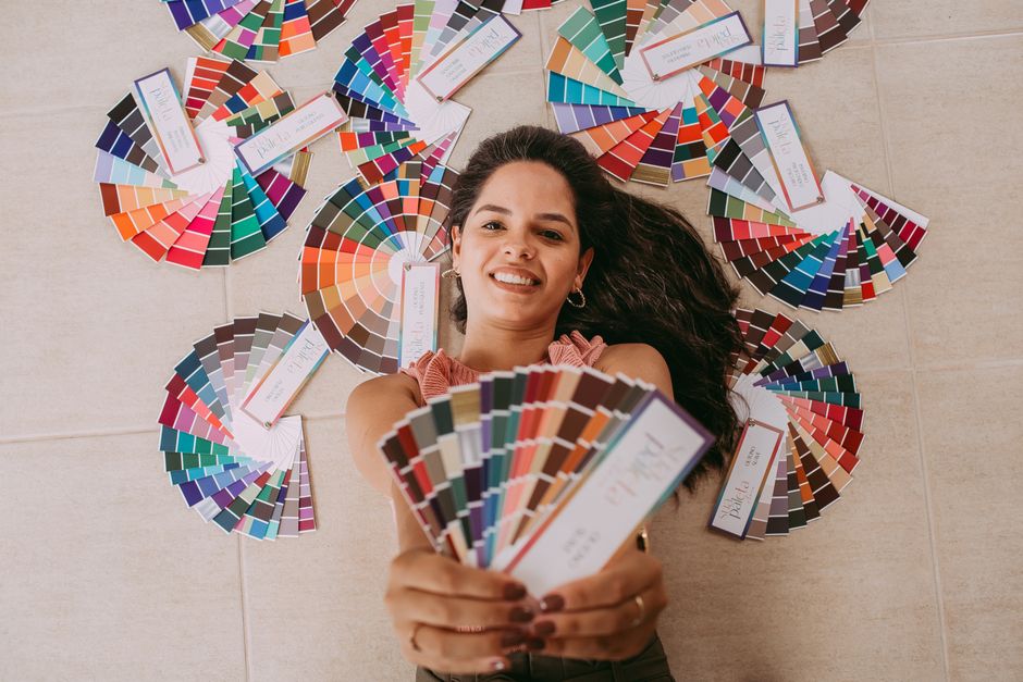 Woman smiling while holding vibrant color swatches, surrounded by color wheels.